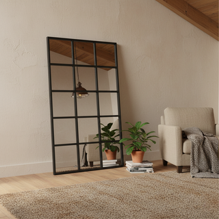 Large standing mirror reflecting a stylish bedroom with floral wallpaper, enhancing space and brightness.