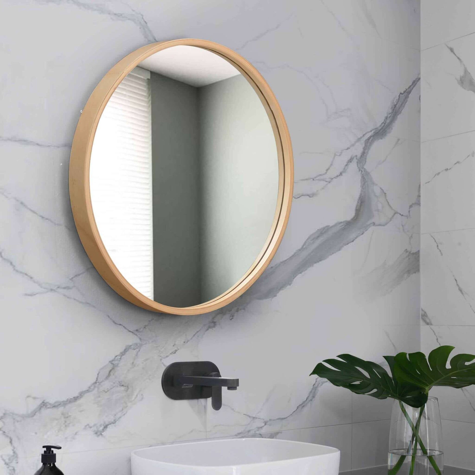Round 685 Mirror with natural wood frame against marble wall, enhancing modern bathroom decor.