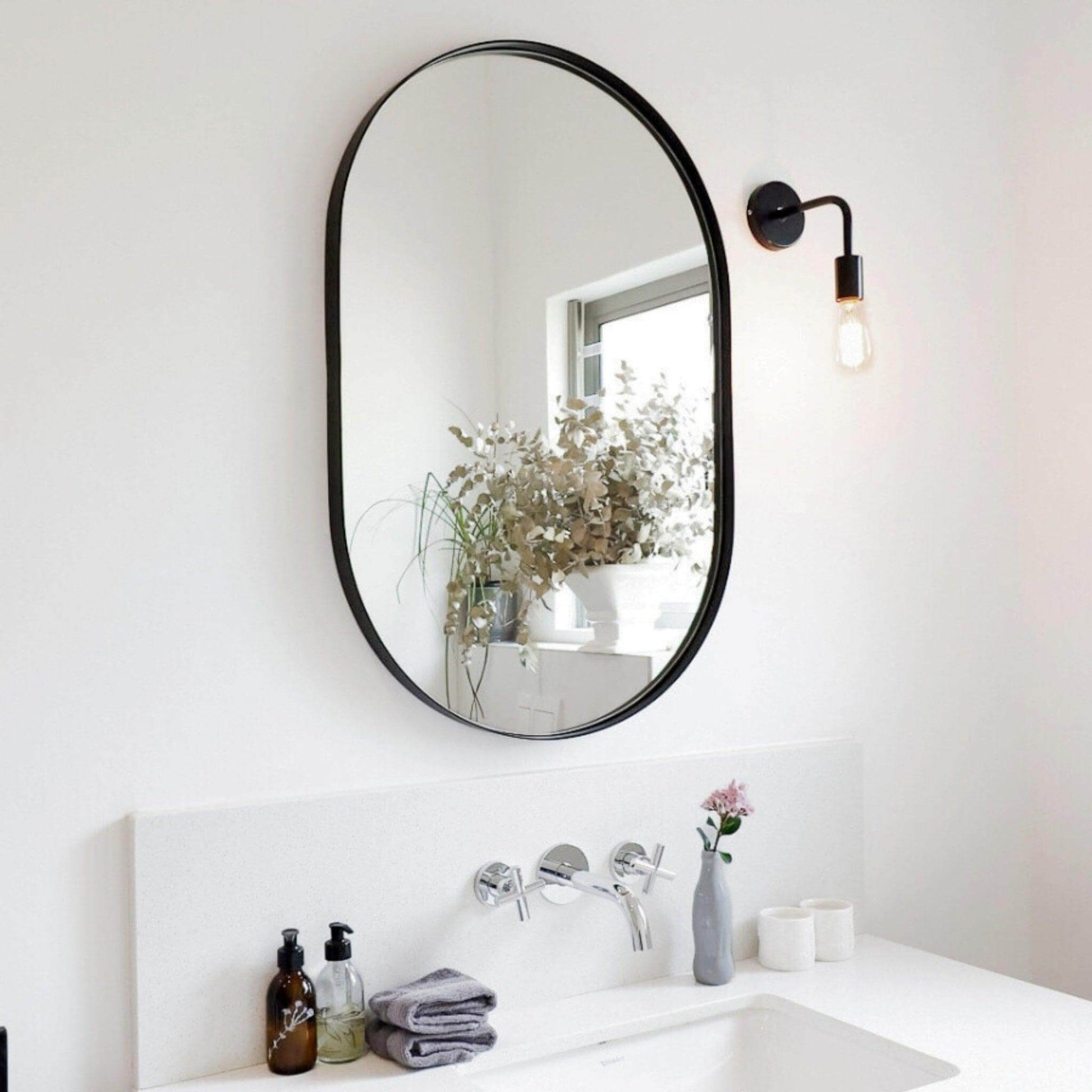 Aura Mirror - Small in a stylish bathroom setting with natural light and decorative plants.