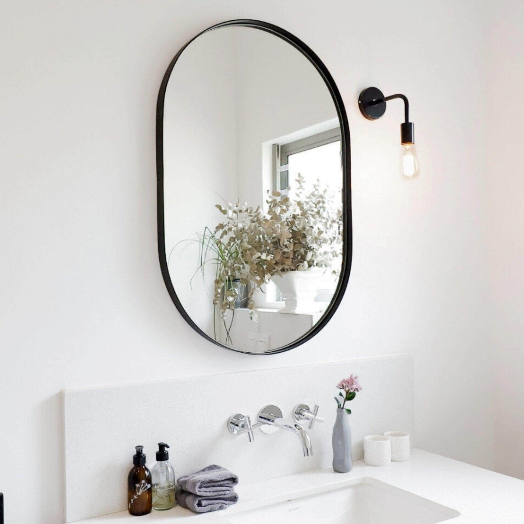 Aura Mirror - Small in a stylish bathroom setting with natural light and decorative plants.