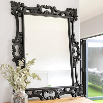 Cove Mirror in black, displayed in a living room setting with classical decor elements.