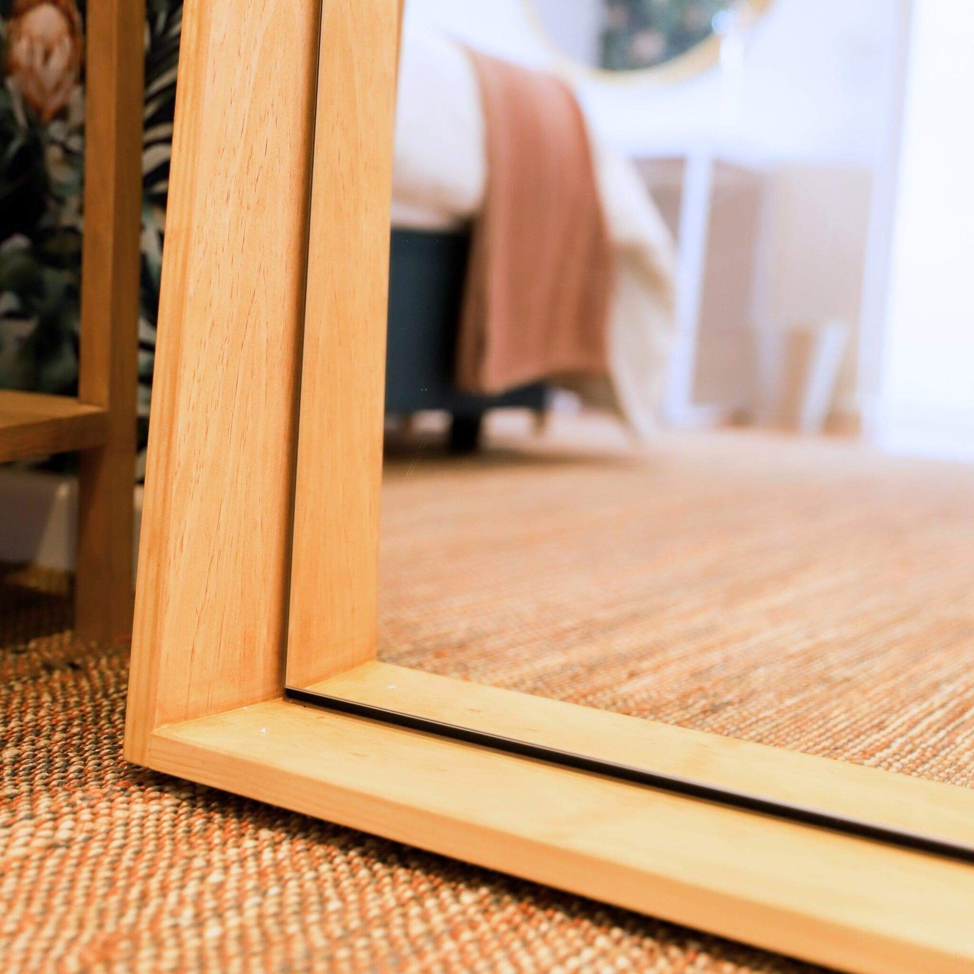 Jupiter Mirror with wood-styled frame reflecting modern elegance in a chic interior setting.