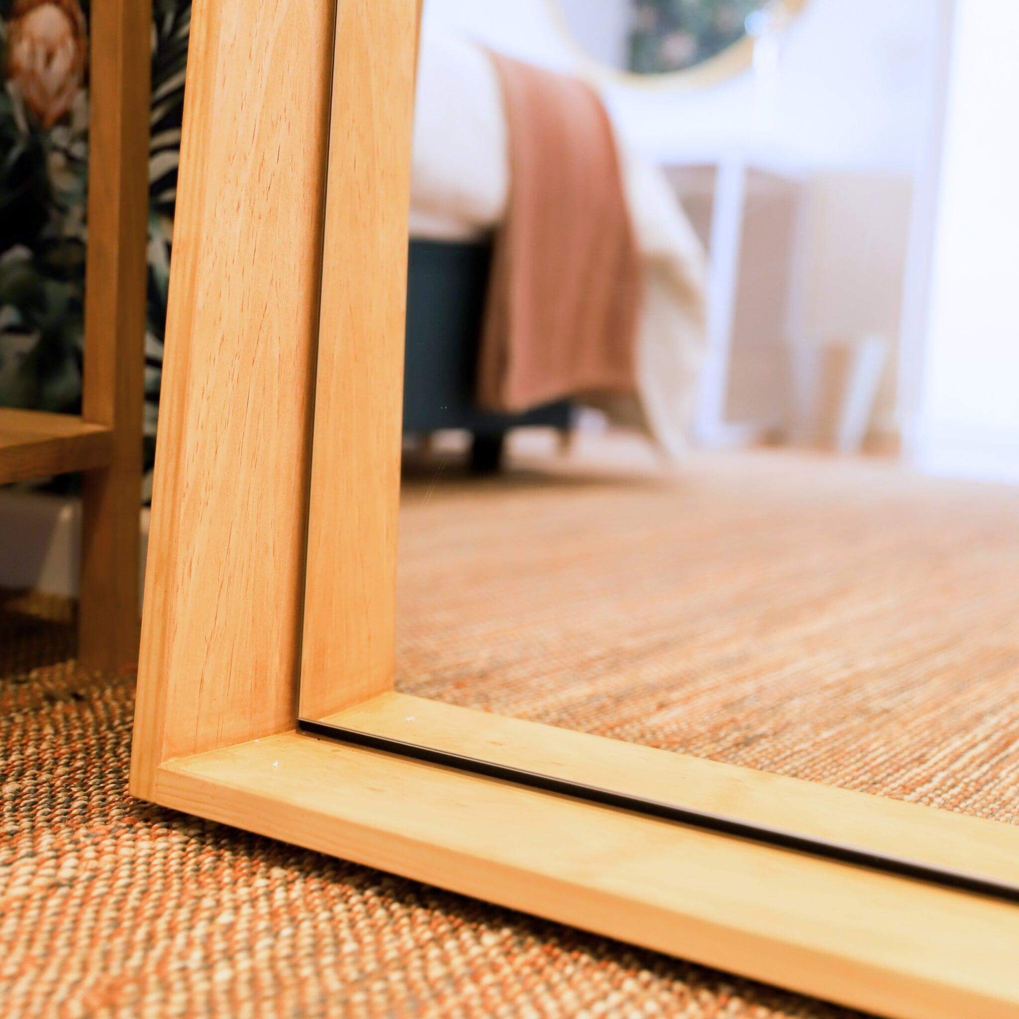 Jupiter Mirror with wood-styled frame reflecting modern elegance in a chic interior setting.