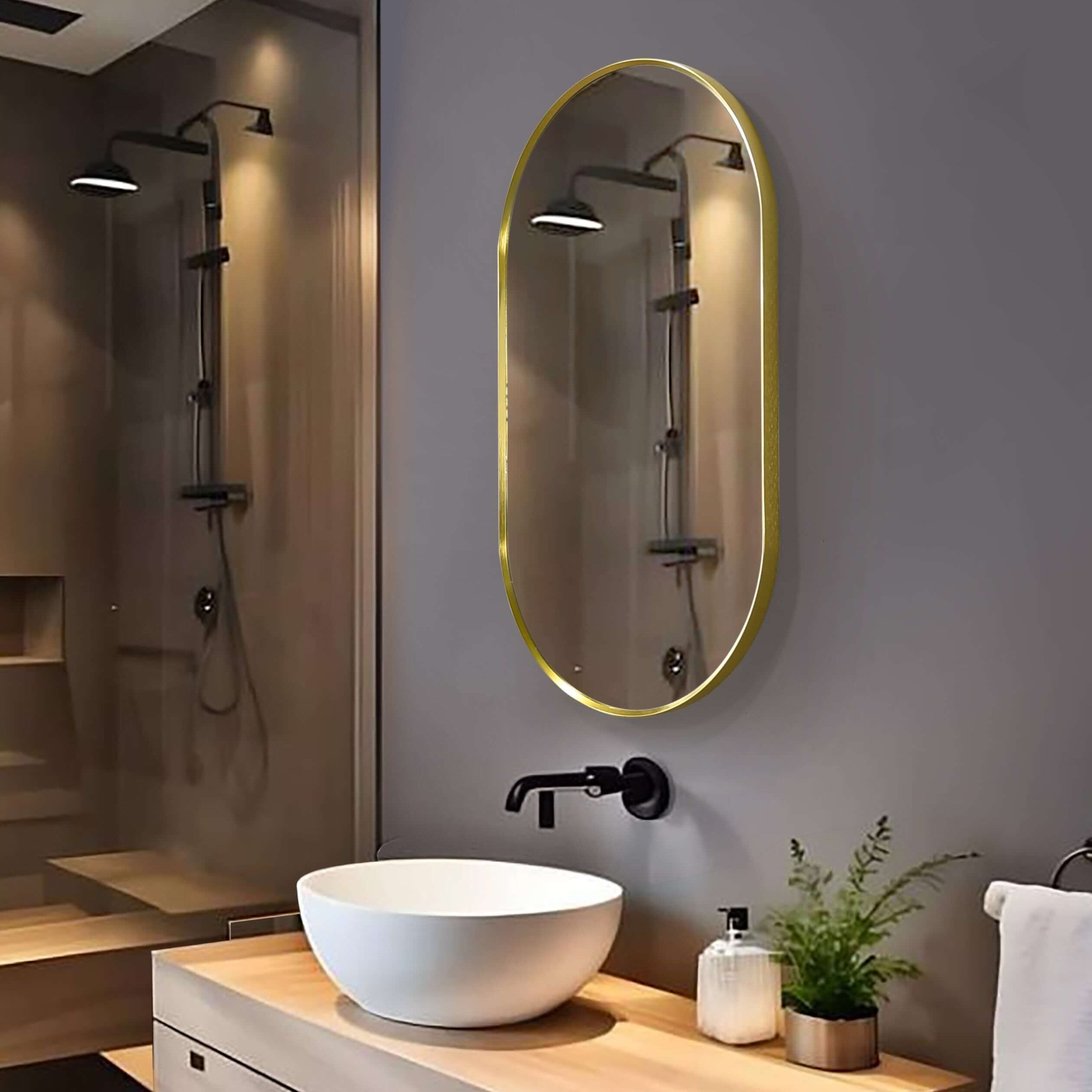 Sculptural oval aluminum framed mirror in gold above a modern bathroom sink with wooden vanity.